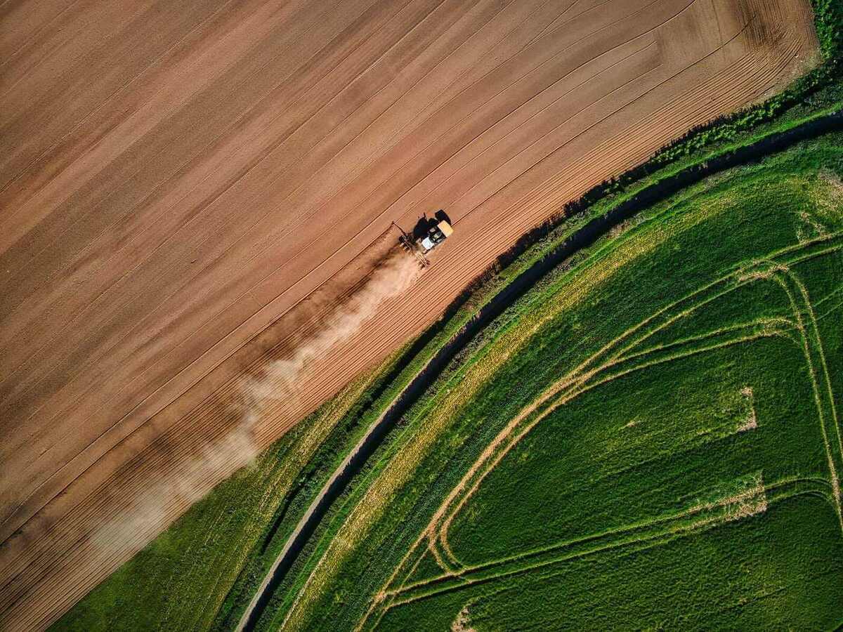 Vista aérea de lavouras e maquinário no campo brasileiro